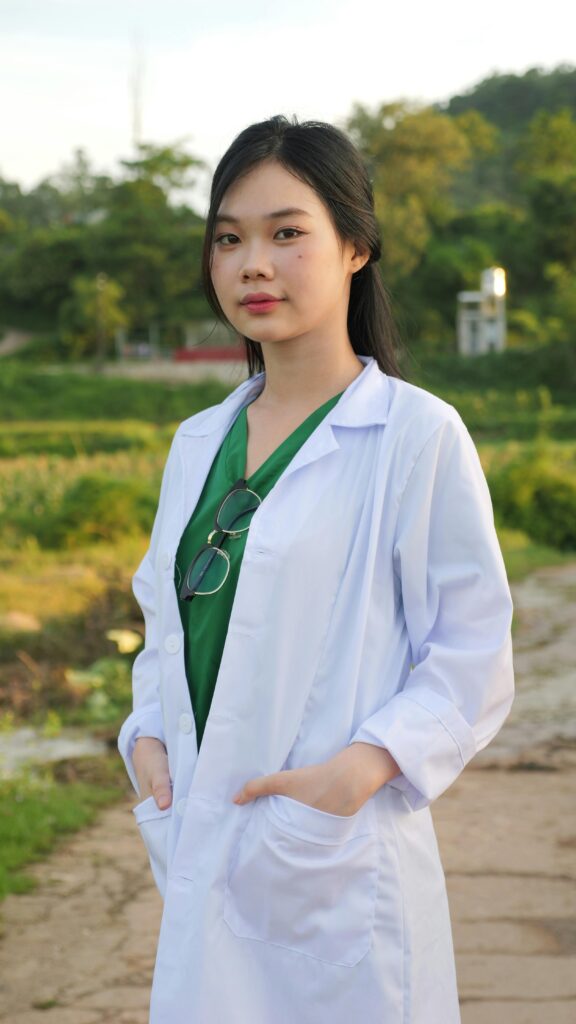 A woman in a white lab coat standing in front of a field